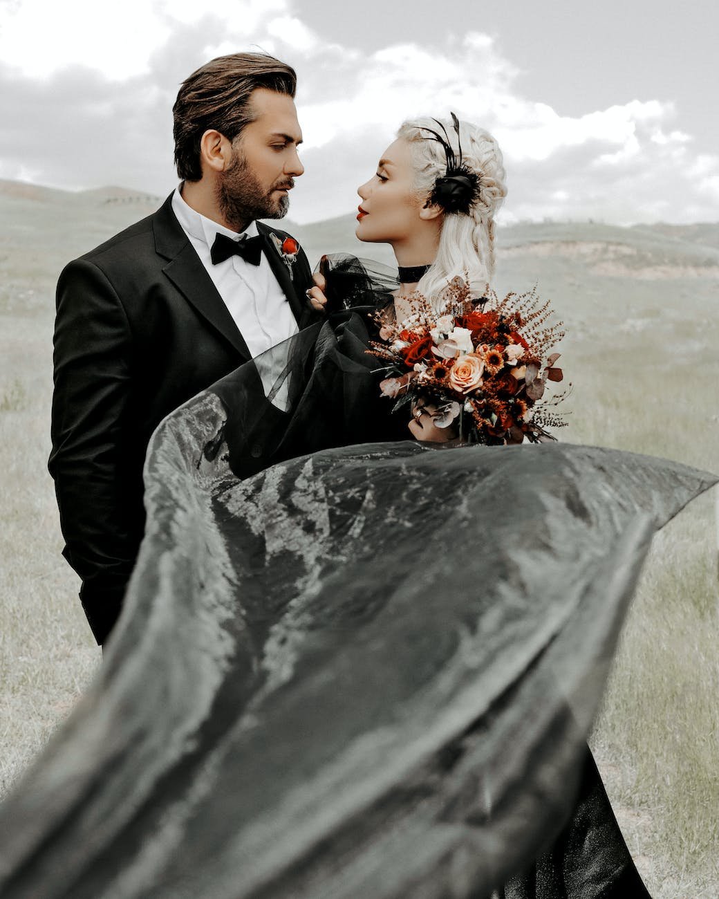 man in black suit holding bouquet of flowers